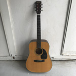 白い壁に立て掛けられたMORRIS アコースティックギター W-18の写真