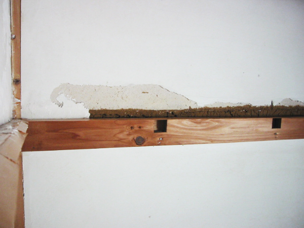 土壁のへこみに漆喰を塗り込んでいる様子