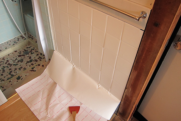 古いタイルの上にカッティングシートを貼る様子