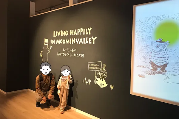 ムーミン谷のしあわせなくらしのかたち展のタイトルをバックに記念撮影する様子