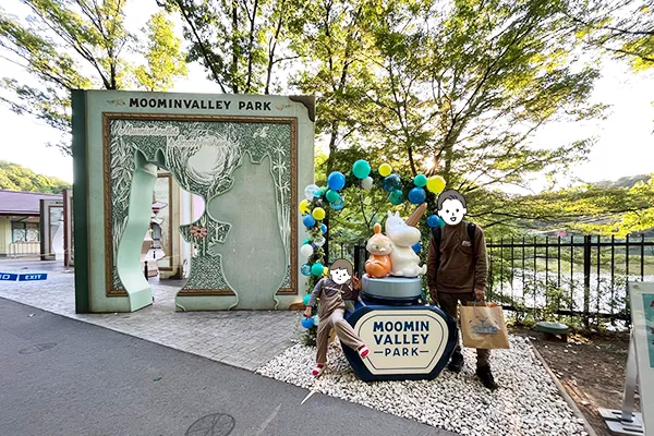 ムーミンのシルエットで切り抜かれた壁を背にして記念撮影する様子