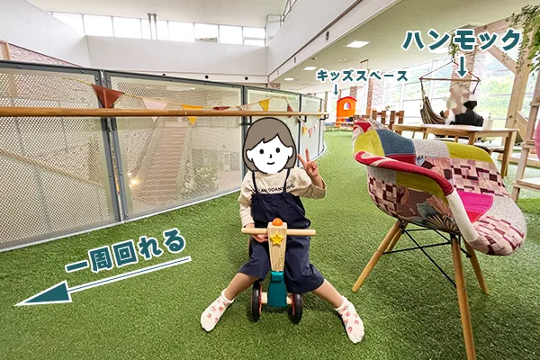 管内２階の人工芝の上で子供が三輪車に乗って遊ぶ様子