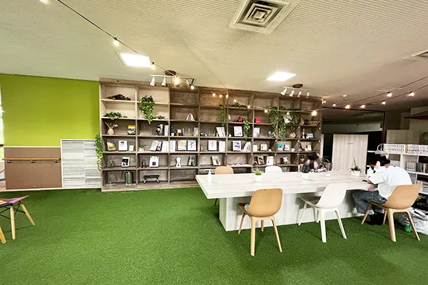 壁一面に本がずらりと並び、人工芝のフロアにテーブルと椅子が並べられた様子