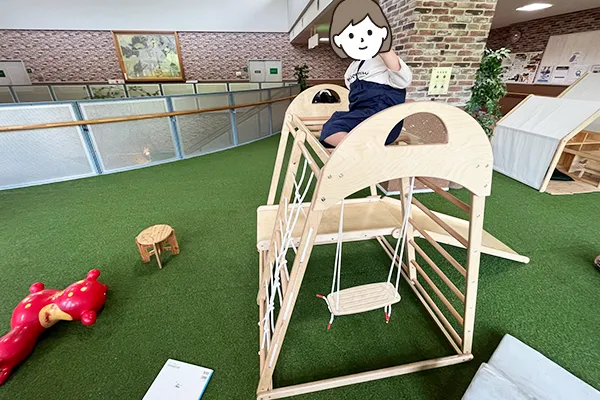 滑り台とブランコが一体になった木製の遊具に登って楽しむ様子