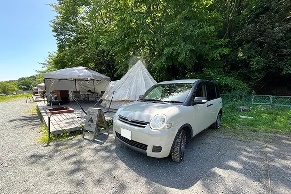 新緑の中のグランピングテントの横にシエンタが泊まっているいる様子